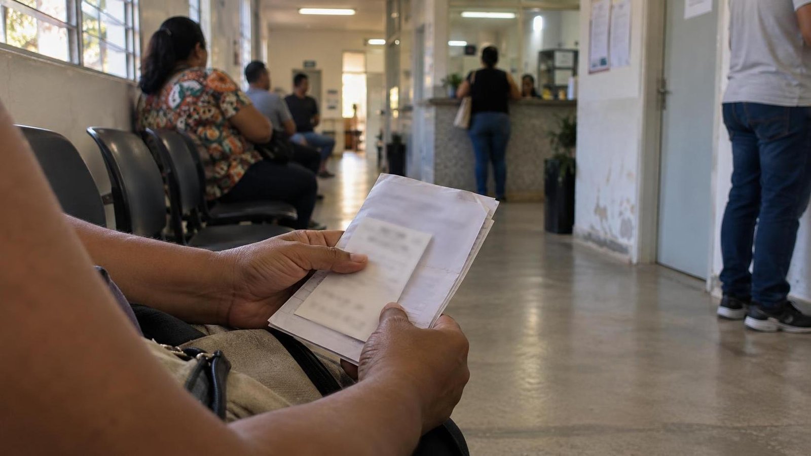 Responsável segura documentos em uma recepção de unidade pública de saúde.